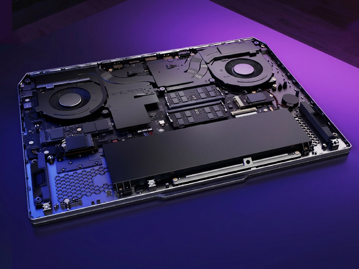 Vista superior do Lenovo LOQ 15IRX9 com tampa removida expondo dissipadores, GPU RTX 4050 e componentes internos com iluminação roxa