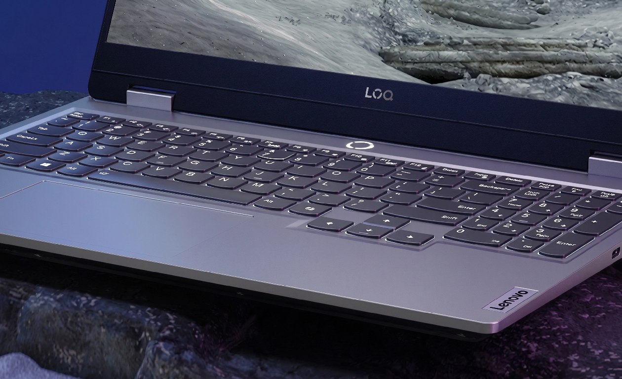 Notebook gamer Lenovo LOQ 15IRX9 em ângulo baixo com fundo rochoso destacando robustez militar MIL-STD-810H e design gamer