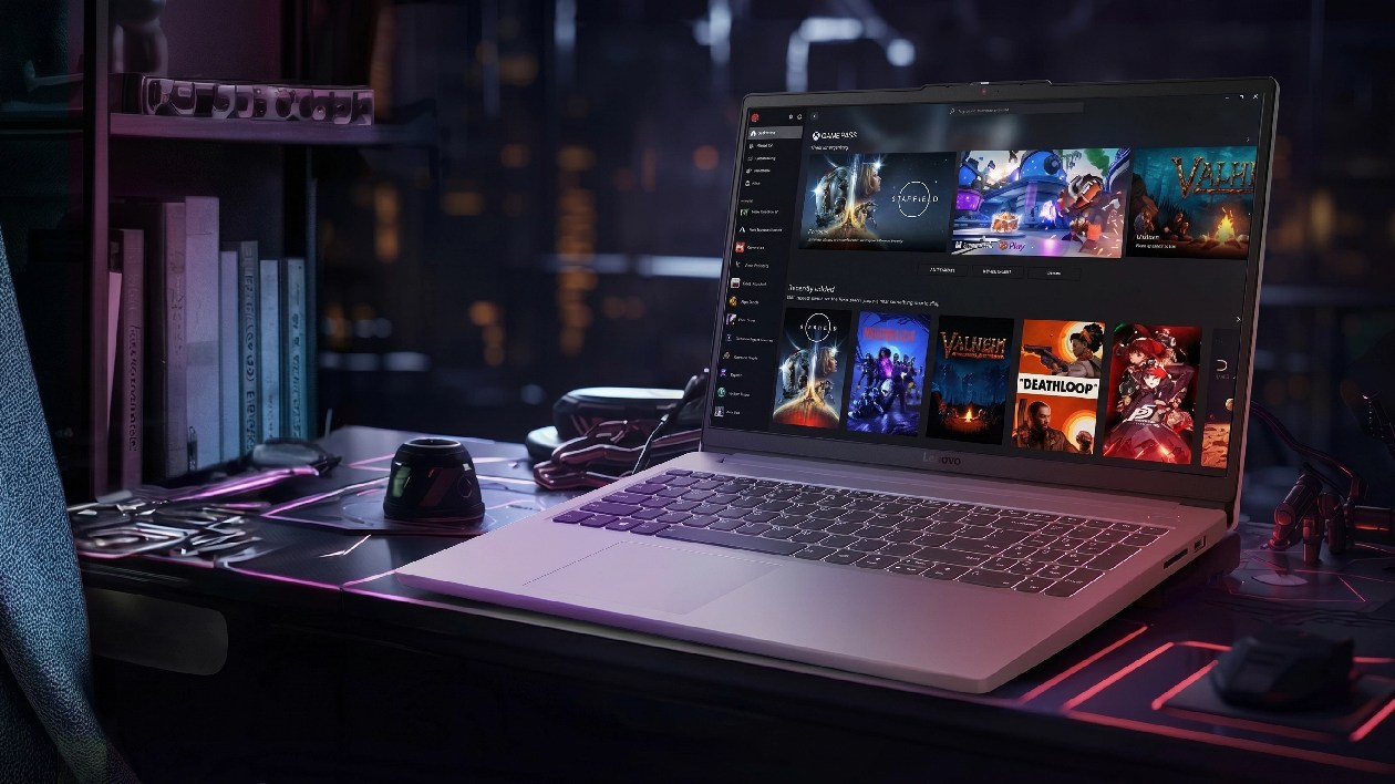 Notebook gamer Lenovo LOQ 15IAX9E Luna Grey em setup de mesa com mouse mousepad fones e livros exibindo biblioteca de jogos na tela