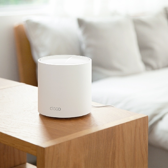Unidade TP-Link Deco X50 branca sobre mesa de madeira em sala de estar integrada ao ambiente dom&eacute;stico