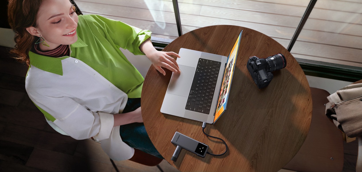 HUB USB-C Ugreen Uno CM888 prata em mesa de madeira ao lado de uma c&acirc;mera mostrando design minimalista premium e portabilidade para criadores de conte&uacute;do