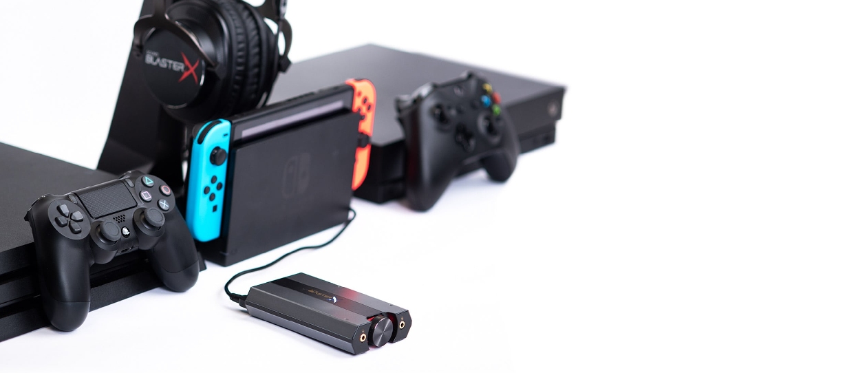 Sound BlasterX G6 sobre fundo branco cercada por controles de PS4, Xbox One, Joy-Cons do Nintendo Switch e headset Sound BlasterX