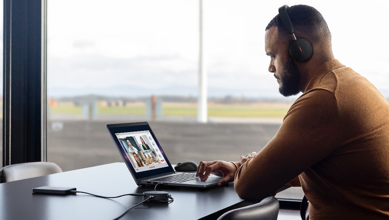 Profissional utilizando o Dell Pro DA326 em reunião virtual via notebook com headset sem fio e armazenamento externo conectado