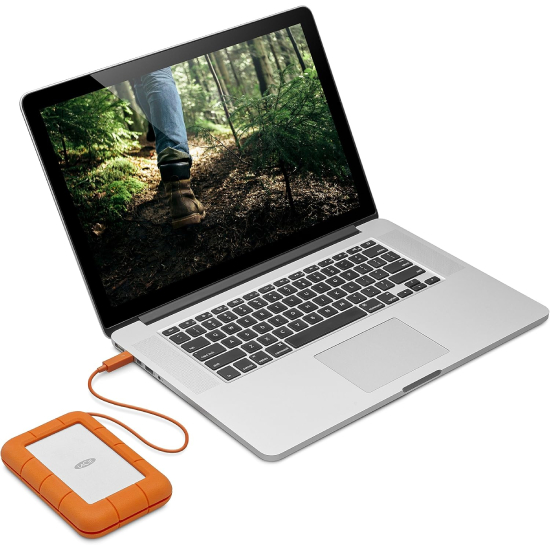 HD externo LaCie Rugged conectado a MacBook Pro exibindo foto de caminhada na natureza