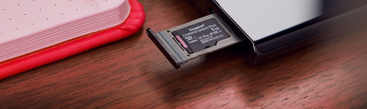 Cartão microSD Kingston Canvas Select Plus 1TB na gaveta de um smartphone sobre mesa de madeira