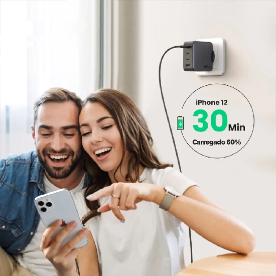 Casal utilizando smartphones conectados ao carregador Ugreen na tomada em ambiente doméstico